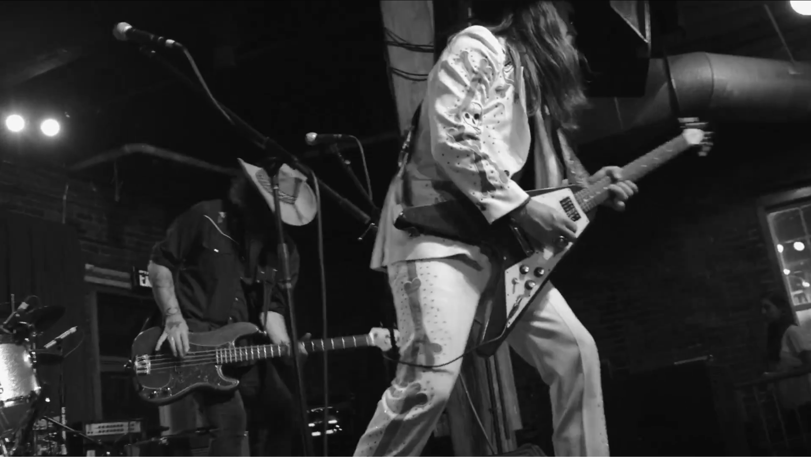 Black-and-white image of Leroy Powell in a white Nudie suit playing a Flying V onstage